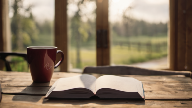 AI-generated image: A wooden table with a red mug and an open book is the main subject.