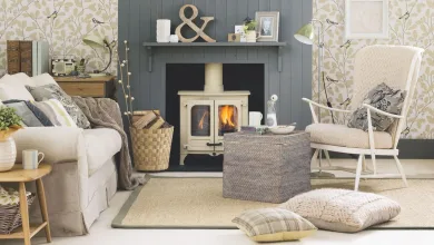Cream log burner in with a blue-grey panelled surround in a light coloured living room, with patterned wallpaper