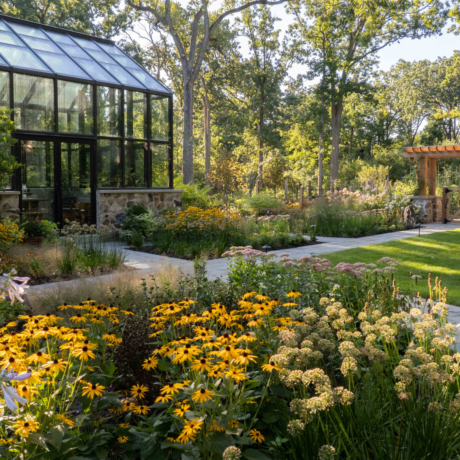 Yellow black-eyed susan and other fall flowers with black conservatory to the rear