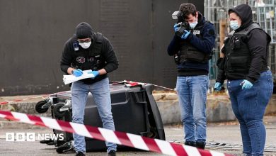 Police officers look at evidences on a site of a petrol station where a man opened fire from his car, killing one person and…