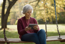 AI-generated image: A seated elderly woman with gray hair is holding a tablet in her hands and looking down at the screen.