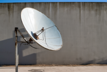 AI-generated image: A satellite dish is mounted on a metal pole against a gray concrete wall.
