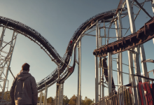 AI-generated image: A man wearing a gray hoodie stands with his back to the viewer, looking at a roller coaster.