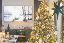Christmas tree decorating with white ornaments and warm gold lighting next to a festive tablescape.
