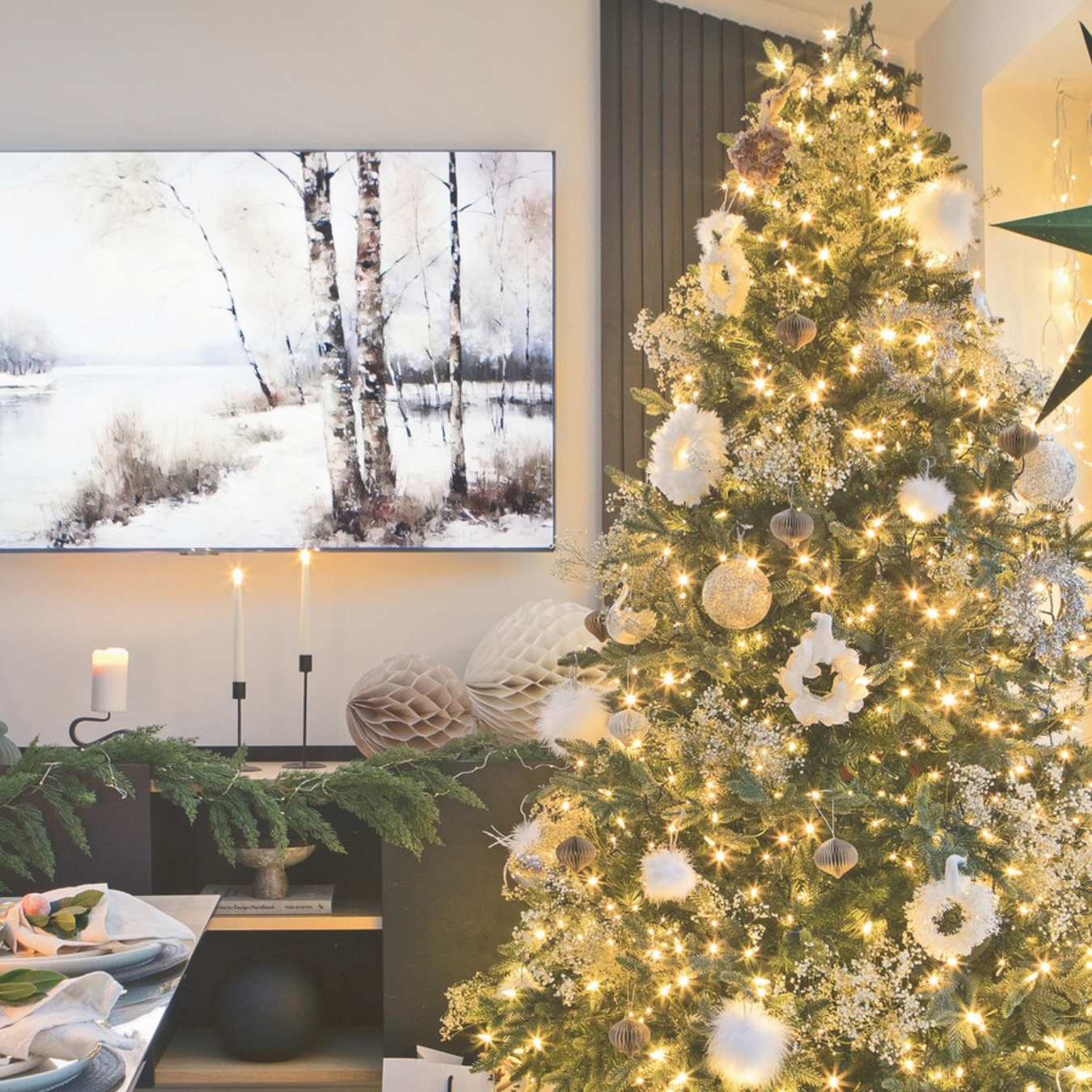 Christmas tree decorating with white ornaments and warm gold lighting next to a festive tablescape.