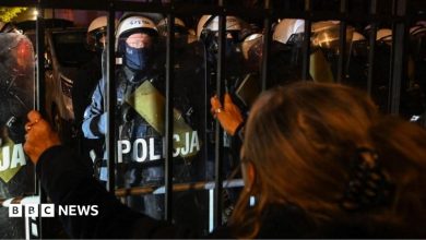 A woman looks at police officers standing guard outside Poland's Constitutional Tribunal in Warsaw. Photo: 30 October 2026